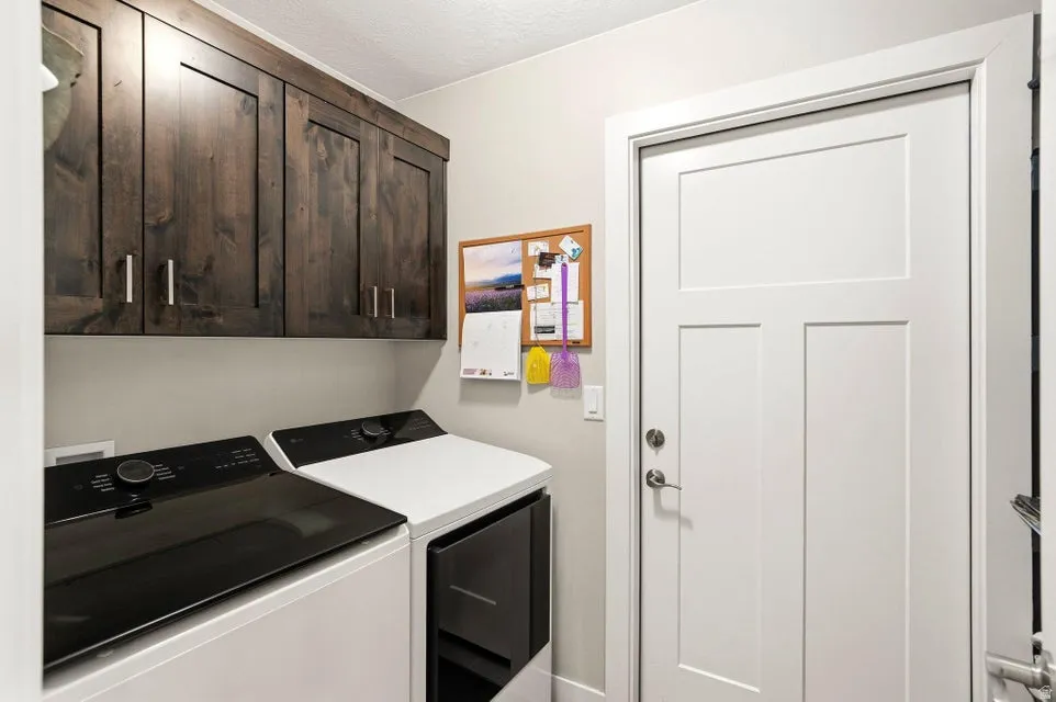 Dedicated utility space featuring dark wood-finish cabinetry with silver hardware, light gray wall paint, and a modern white panel door with brushed nickel hardware
