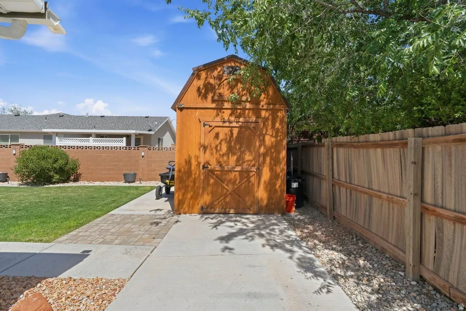 Wood-sided storage shed with barn doors, situated on a paved pathway