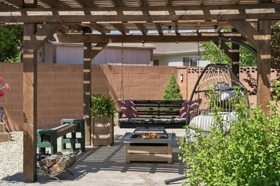 Wood pergola structure providing shade, paver patio, wood-finish fire pit, and block wall perimeter