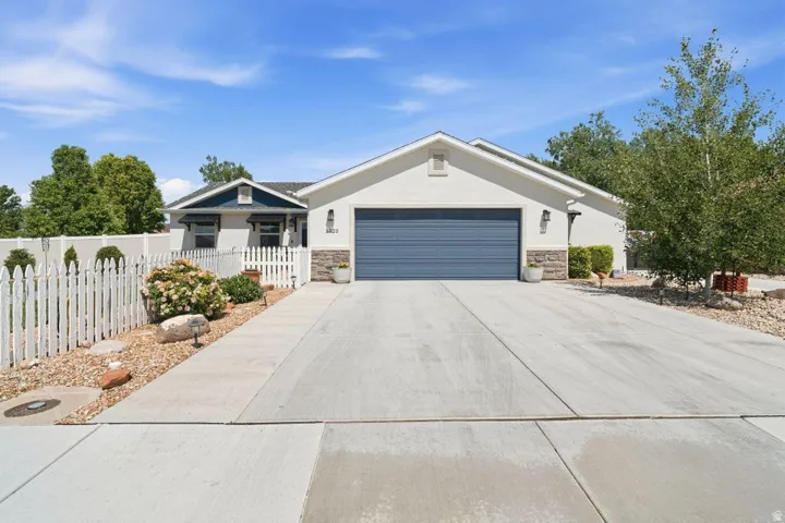 Contemporary stucco exterior with stone accents, featuring a blue garage door and a contrasting blue entry gable