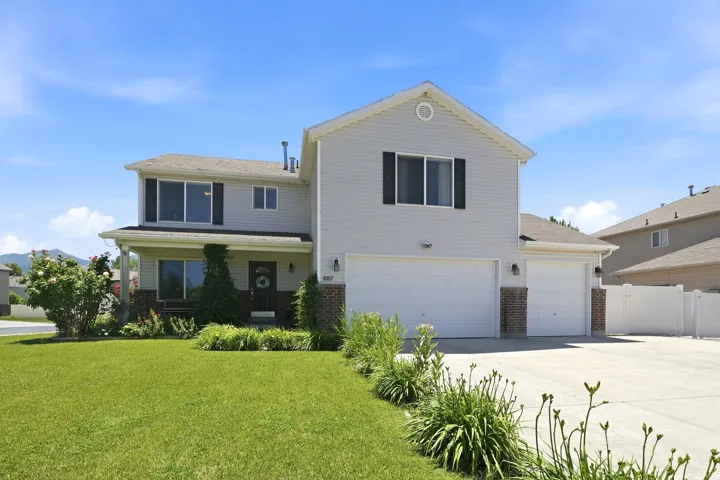 Two-story residence featuring light-colored siding, a covered front porch, and a three-car garage