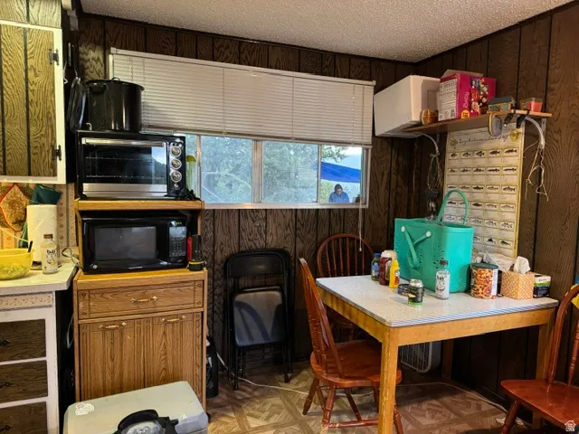 Kitchenette featuring a dining table, wood-finish wall paneling, and a window with horizontal blinds