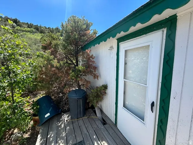 White siding exterior with a green decorative trim, featuring a white door with a screen insert