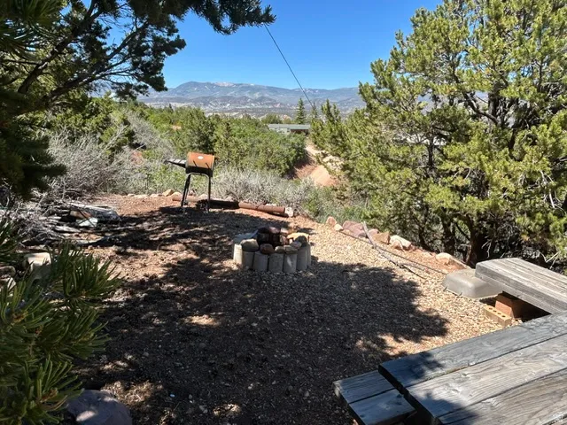 Outdoor entertaining area featuring a built-in fire pit with stone surround, gravel ground cover, and a picnic table