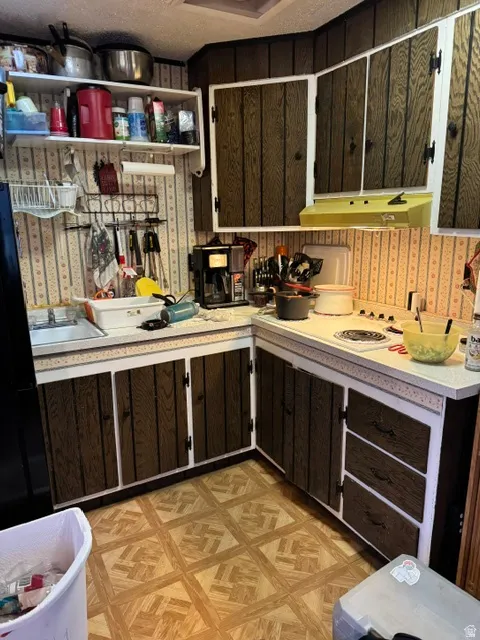 Kitchen featuring wood-finish cabinetry, white countertops, and patterned vinyl flooring