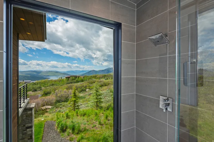 Shower with large format gray tile, glass enclosure, square rain shower head, and chrome fixtures
