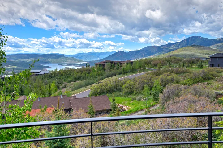 Expansive mountain landscape featuring distant lake, rolling hills, and scattered residences