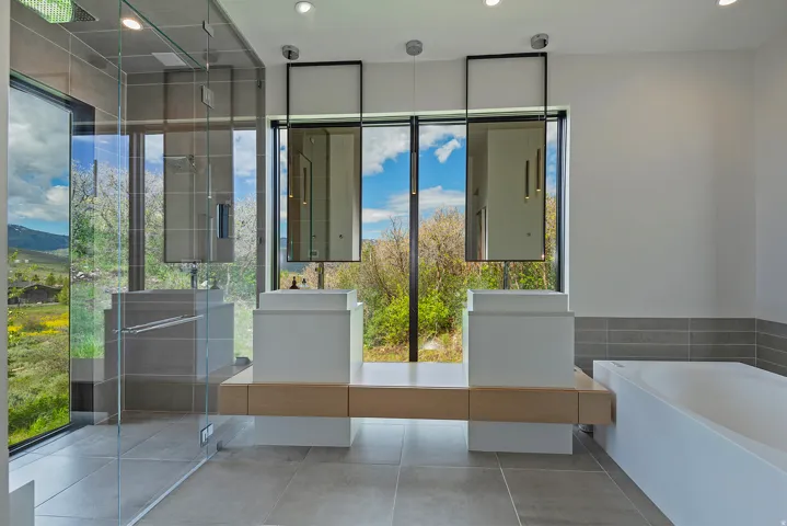 Modern bathroom featuring a double vanity with square vessel sinks, a floating wood-finish countertop, and full-height windows
