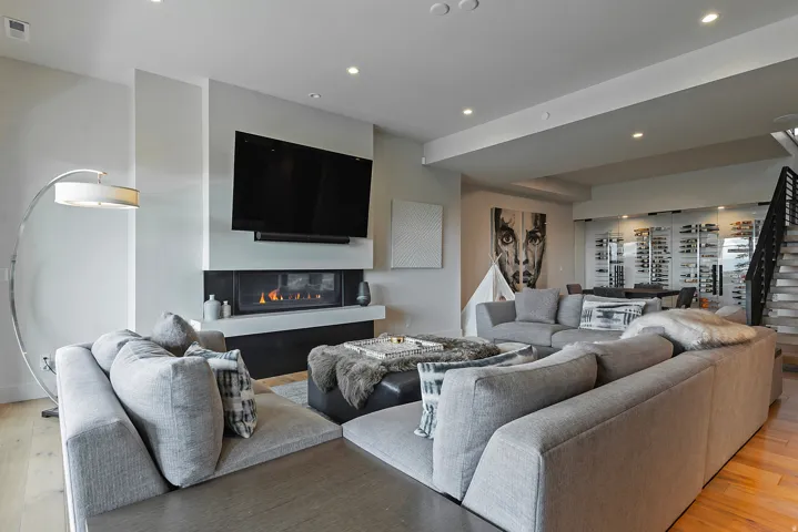 Open-concept living space featuring a modern linear gas fireplace with a white mantel, recessed lighting, and wood-finish flooring