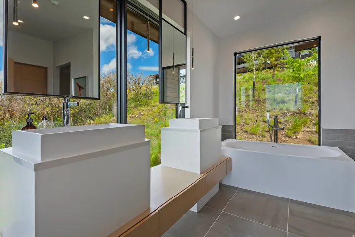 Contemporary bathroom featuring dual vessel sinks on an expansive vanity with wood-finish accents