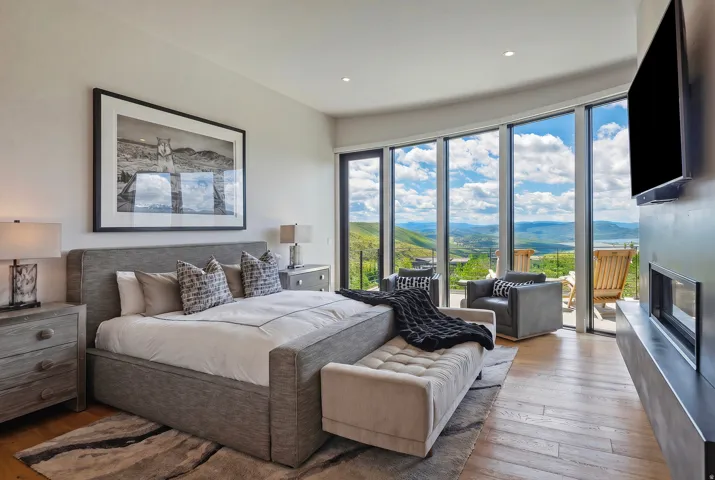 Bedroom featuring extensive floor-to-ceiling windows, wood-finish flooring, and a modern fireplace