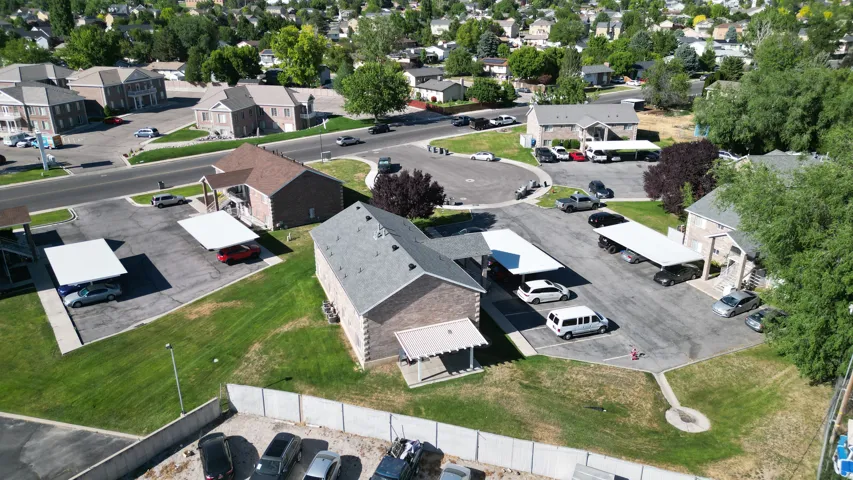 Multi-building property featuring brick and siding exteriors, gabled roofs, multiple carport structures, paved parking areas, and mature landscaping
