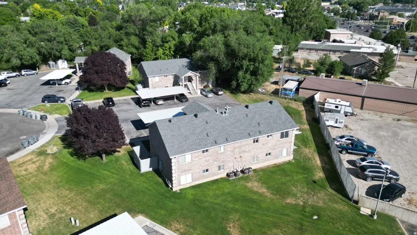 Multi-building property featuring brick and siding exteriors, gray shingle roofs, and surface parking