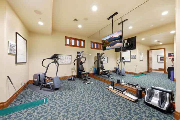 Dedicated fitness space featuring patterned carpet flooring, recessed lighting, and a mirrored wall