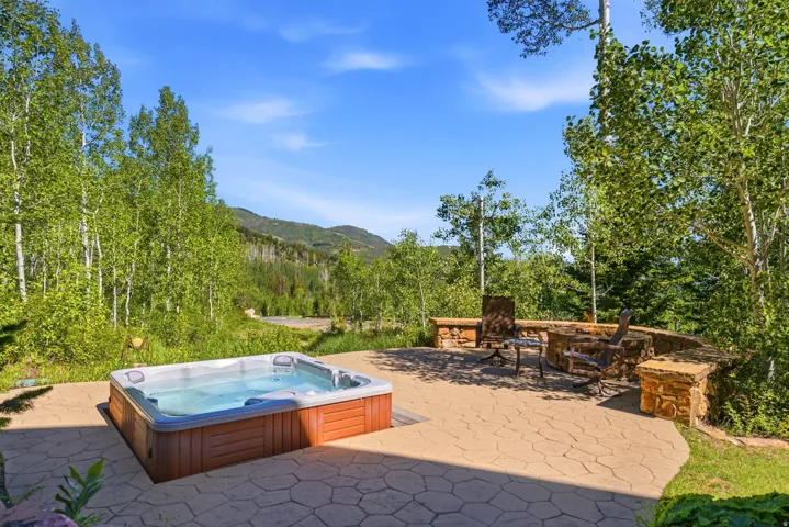 Outdoor patio featuring a built-in hot tub, stamped concrete paving, and a stone-built fire pit area