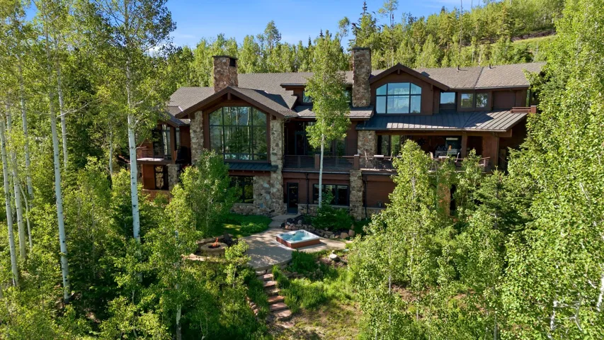 Multi-level residence featuring stone accents, a deep brown facade, and a large window wall