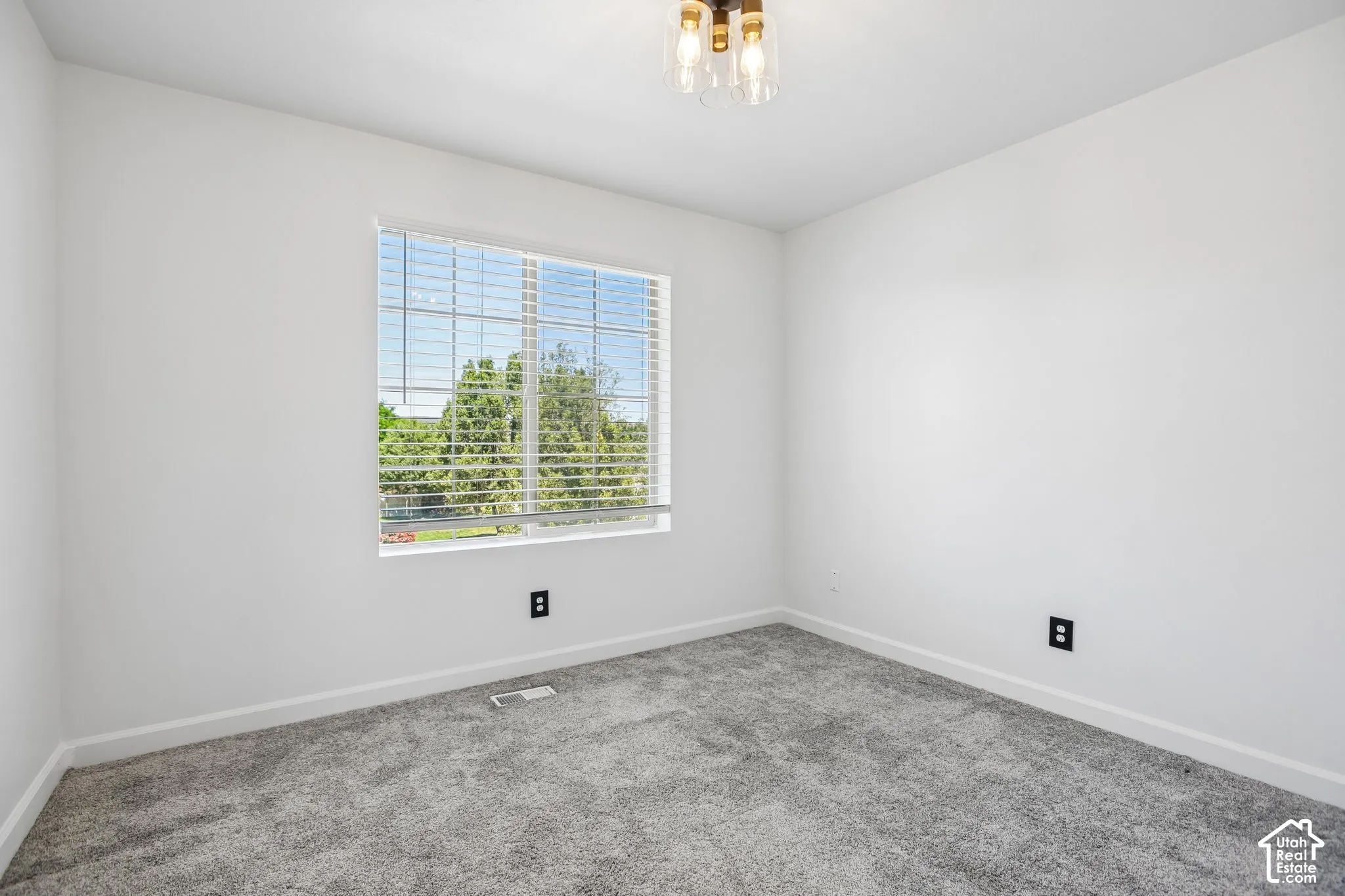 Bright room featuring a large window with blinds, neutral wall paint, and gray carpet
