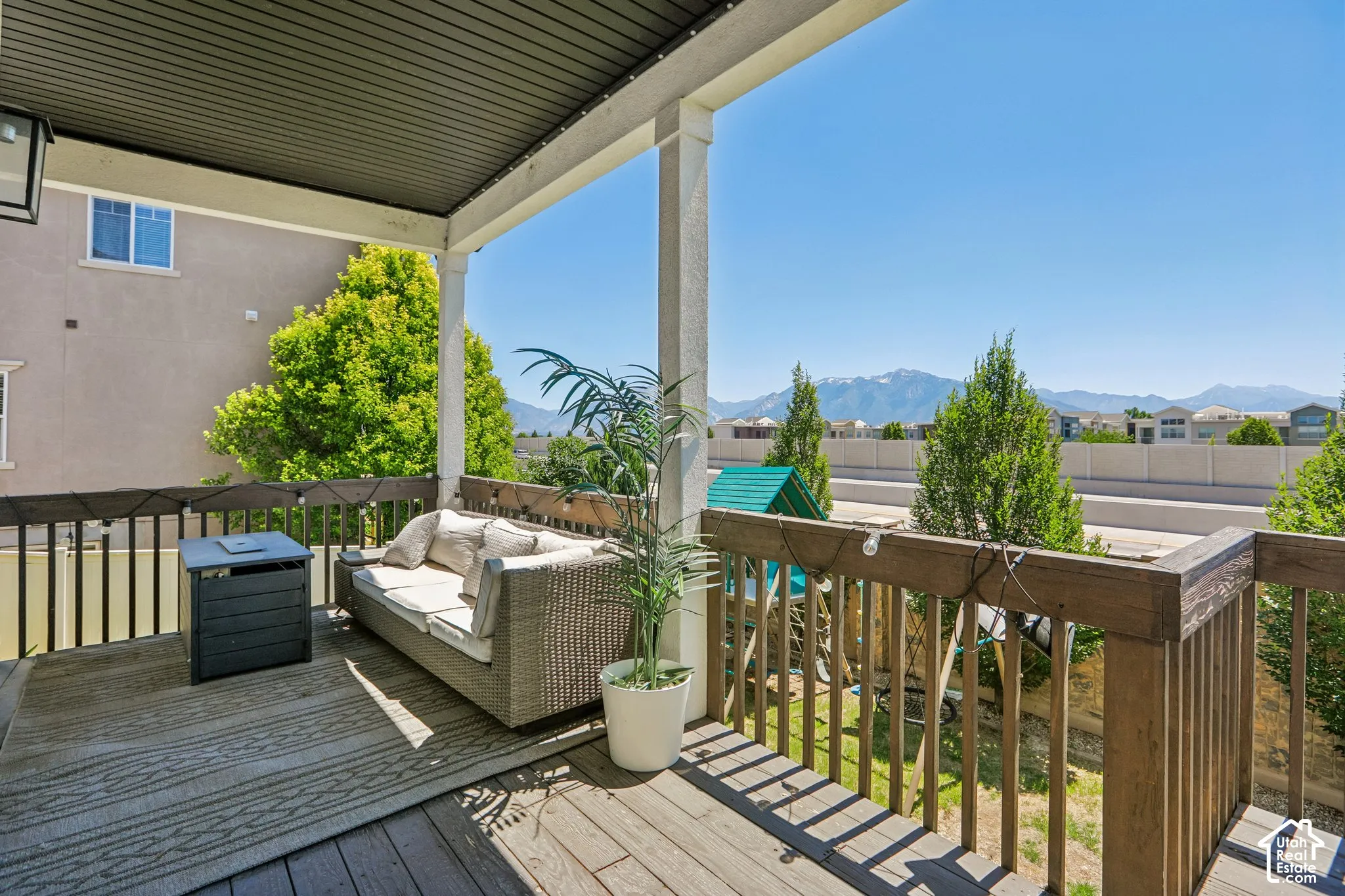 Covered balcony featuring wood-finish flooring, white support columns, and a dark slatted ceiling