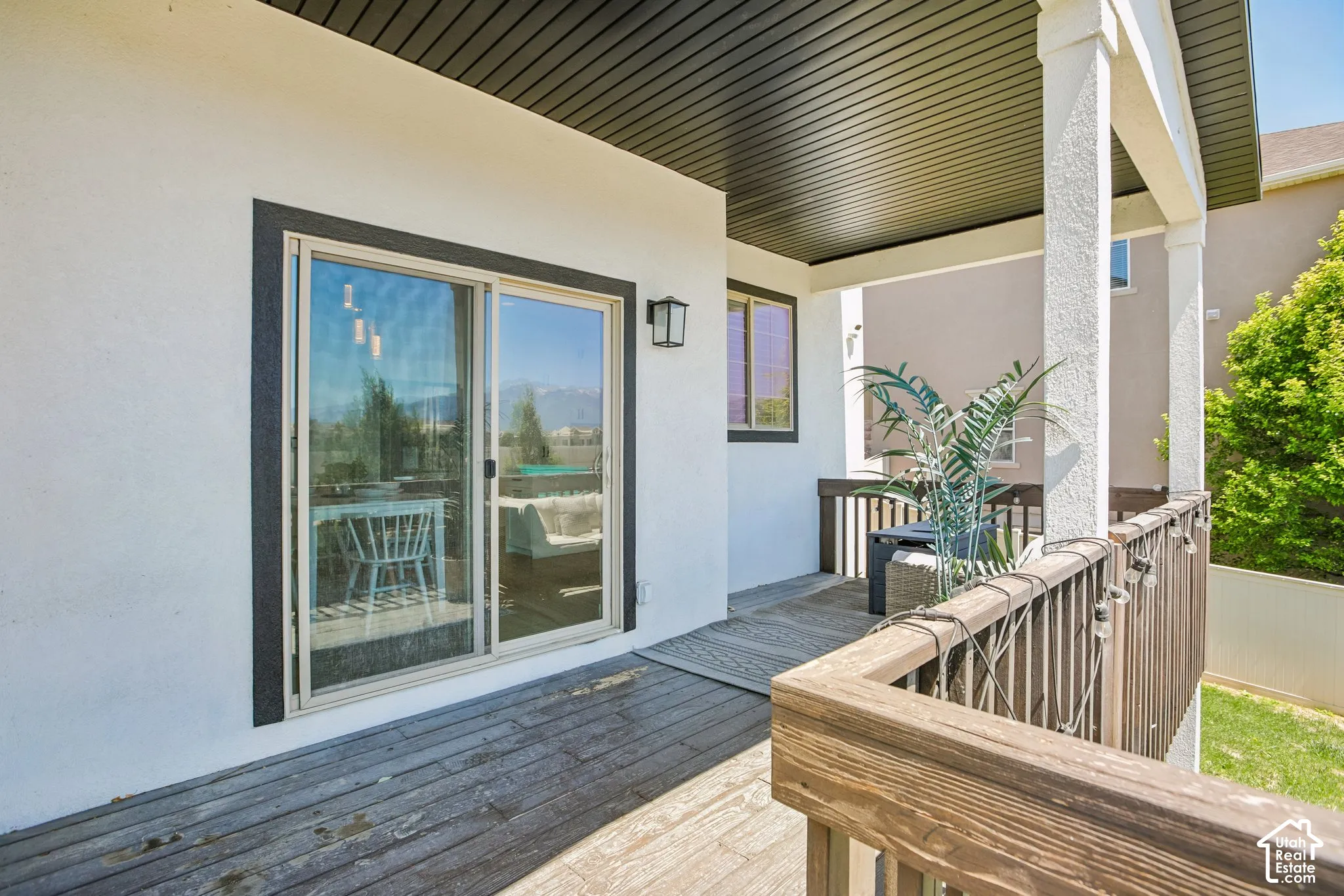 Covered wood-finish deck with a wood railing and white columns