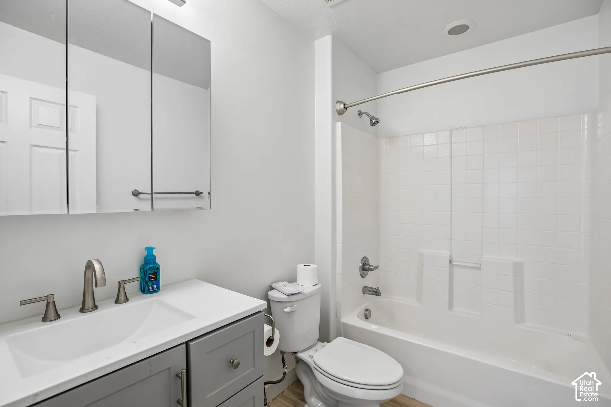 Bathroom featuring a single vanity with a white countertop and undermount sink, brushed nickel faucet, and a medicine cabinet with integrated lighting