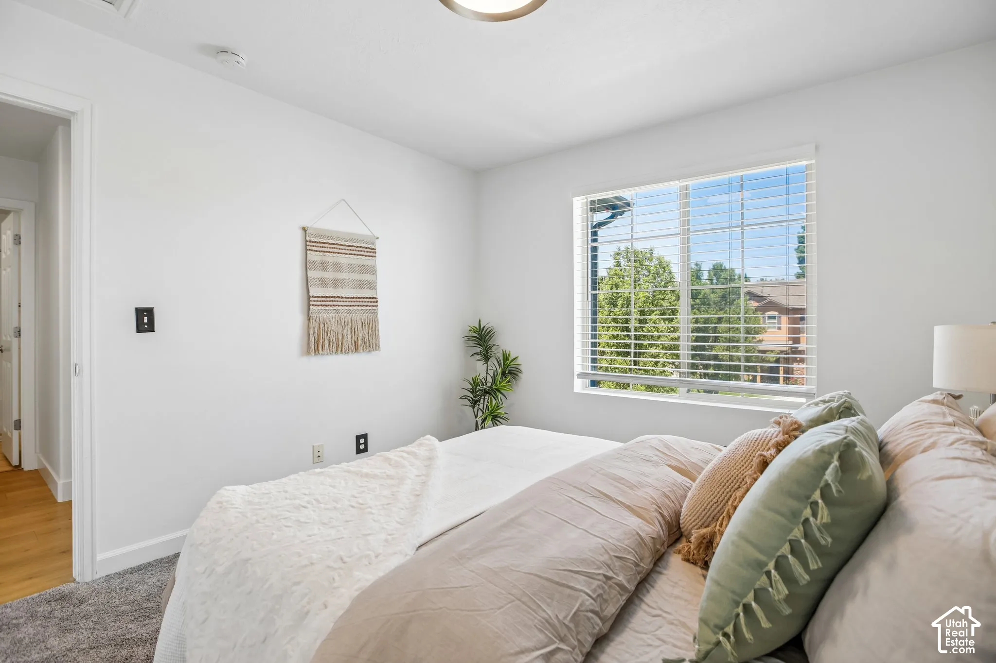 Bright room featuring a large window with blinds, light gray carpet, and white walls