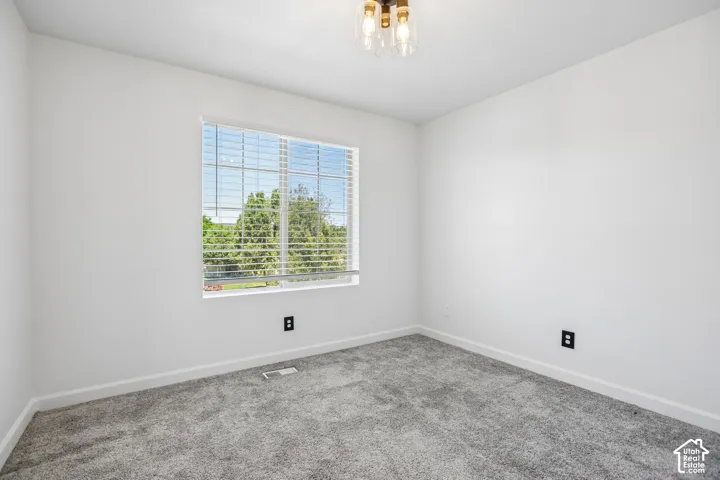 Bright room featuring a large window with blinds, neutral wall paint, and gray carpet