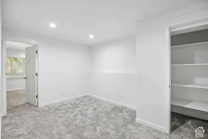 Neutral-toned room featuring plush carpeting and recessed ceiling lighting