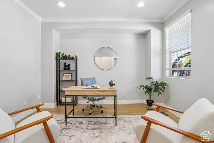 Dedicated office space featuring recessed lighting, crown molding, a large window with blinds, wood-finish flooring, and a decorative alcove