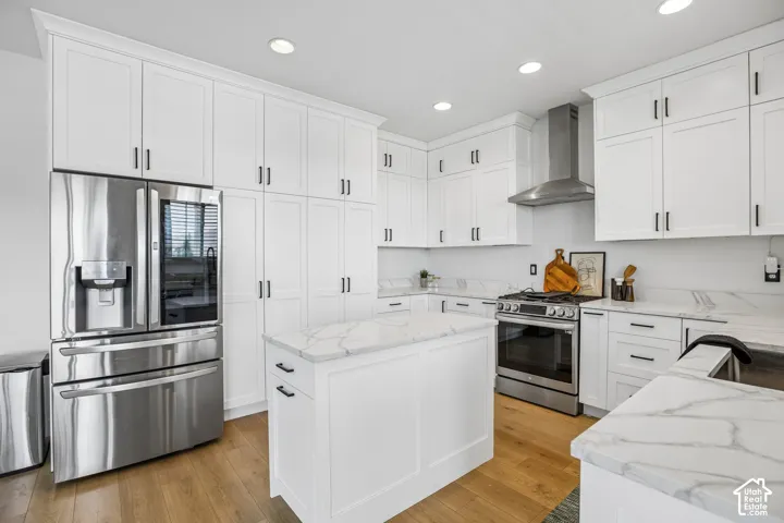 Bright kitchen featuring white shaker cabinetry, stainless steel appliances, a center island, marble-patterned countertops, and wood-finish flooring