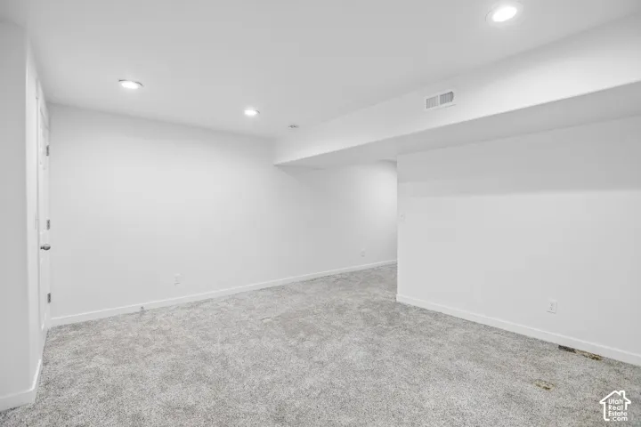Spacious room featuring new carpeting, recessed lighting, and a neutral white color palette