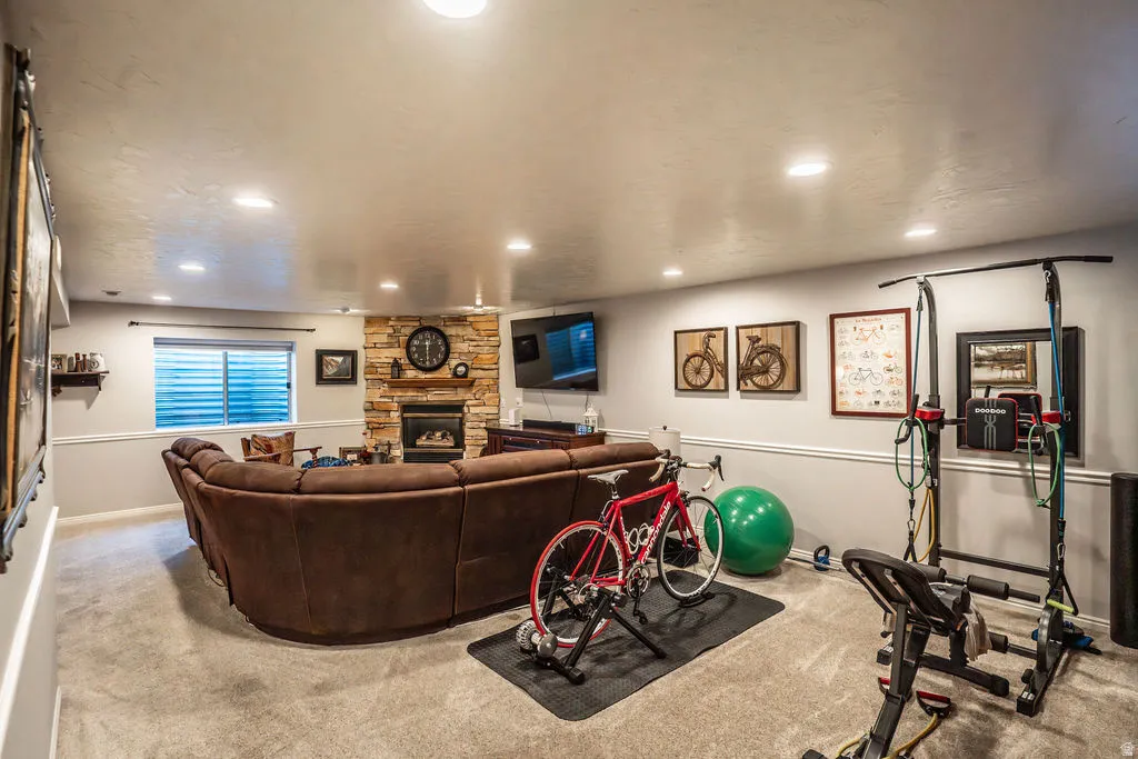 Spacious lower-level area featuring recessed lighting, carpeted flooring, and a stone-clad fireplace