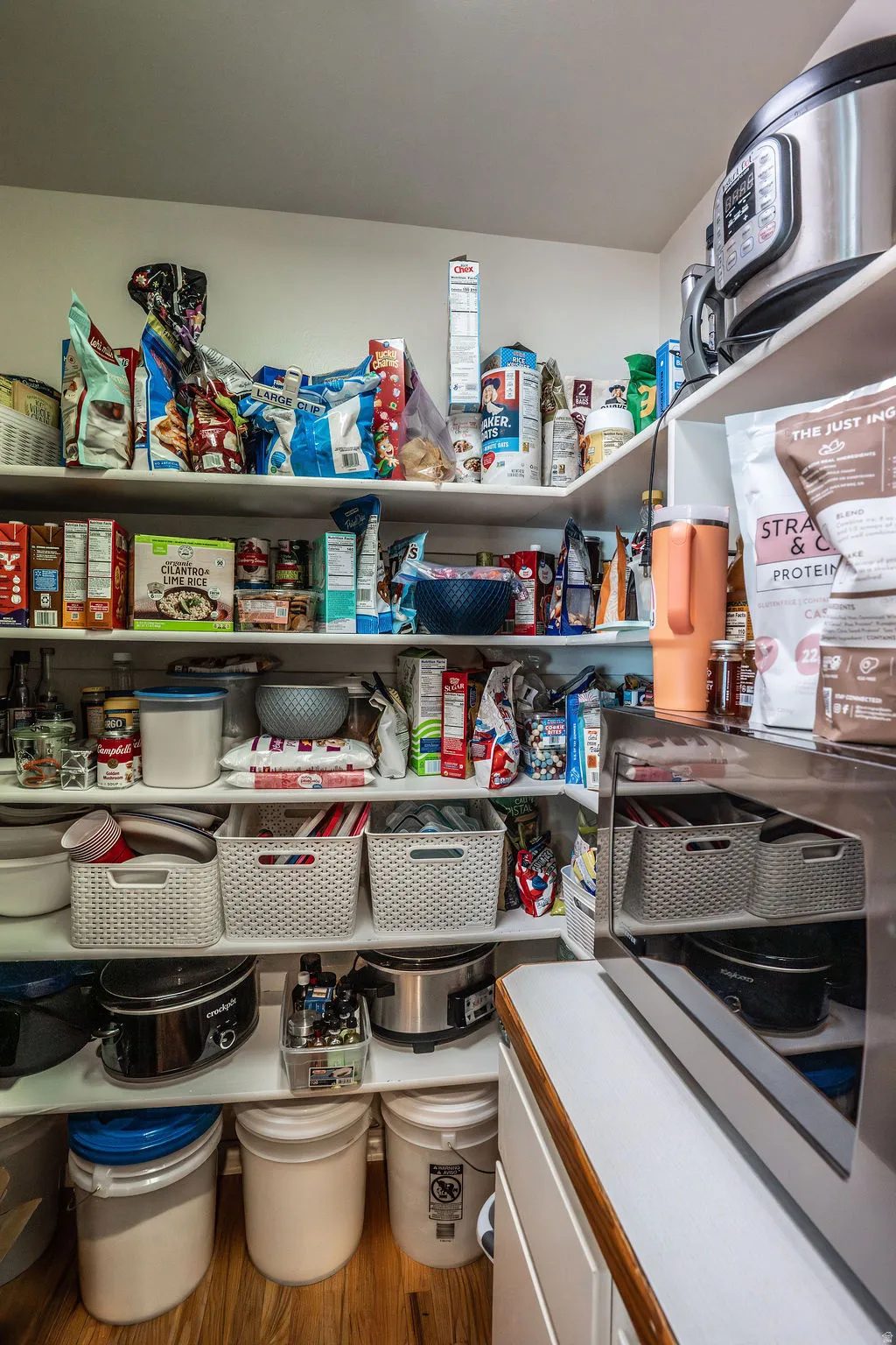 Walk-in pantry featuring white shelving, wood-finish flooring, and a counter space with a wood edge
