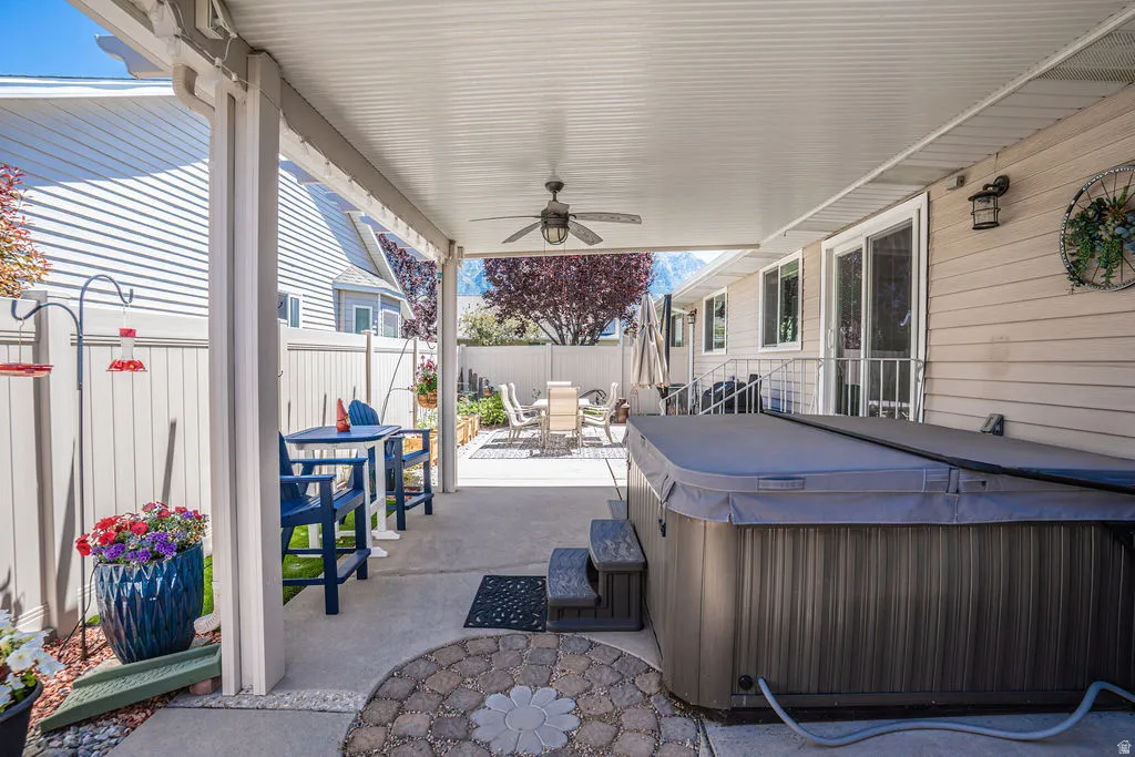 Covered patio featuring a ceiling fan, hot tub, and concrete flooring