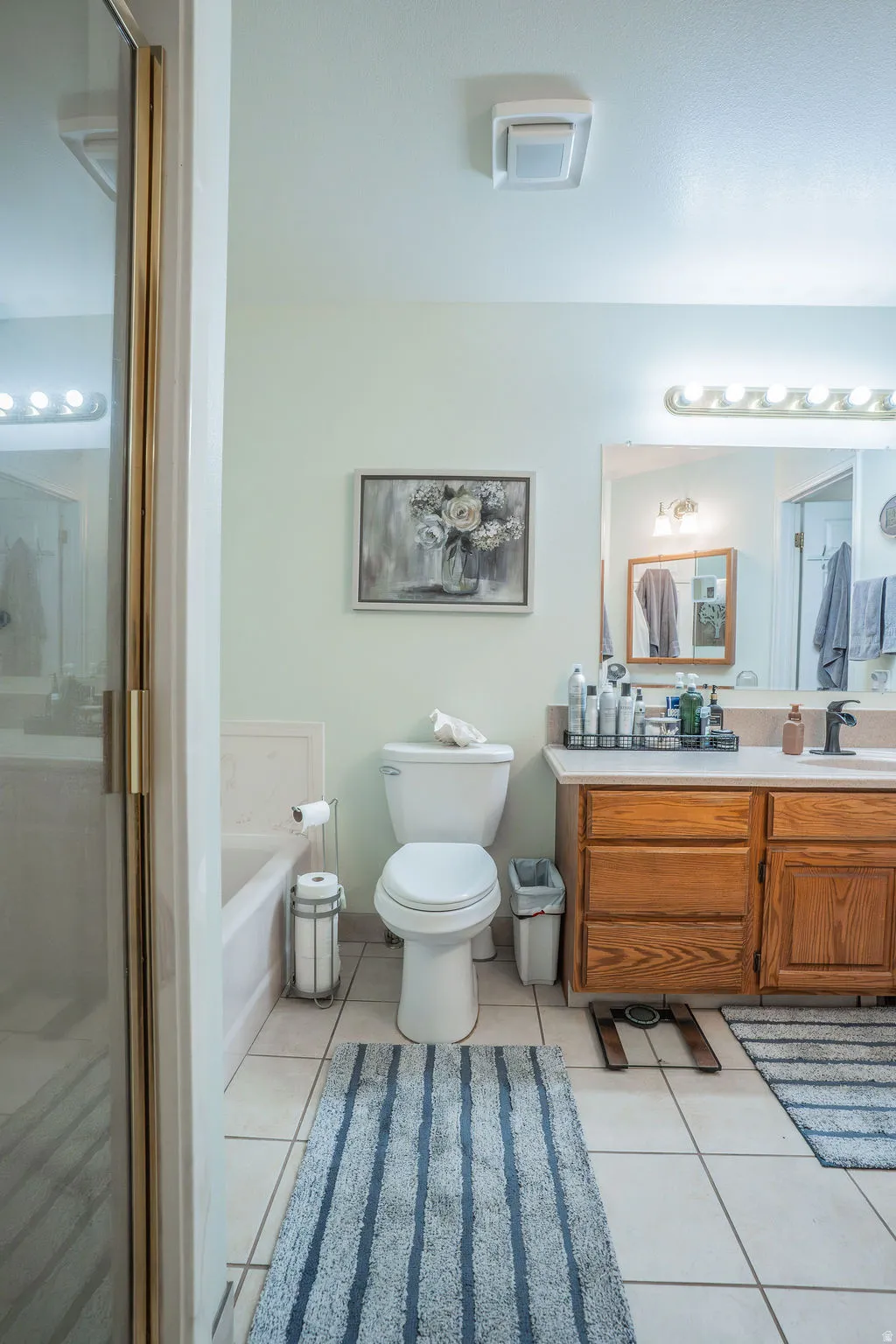 Bathroom featuring a built-in tub, white toilet, and tile flooring
