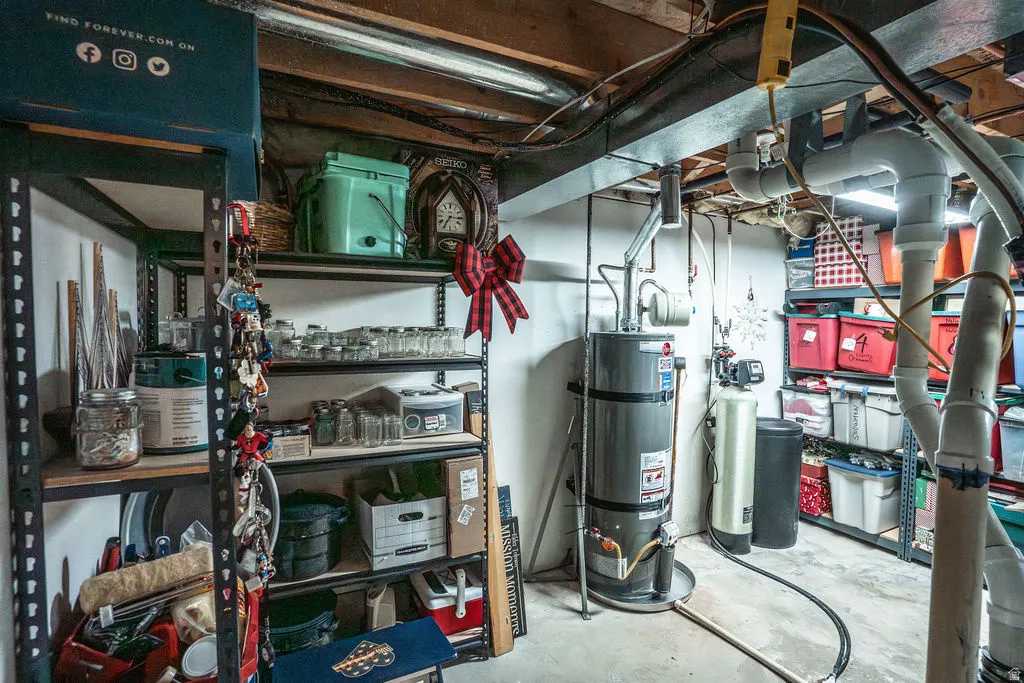 Basement utility area featuring a water heater, water treatment system, exposed ceiling joists, and overhead ductwork