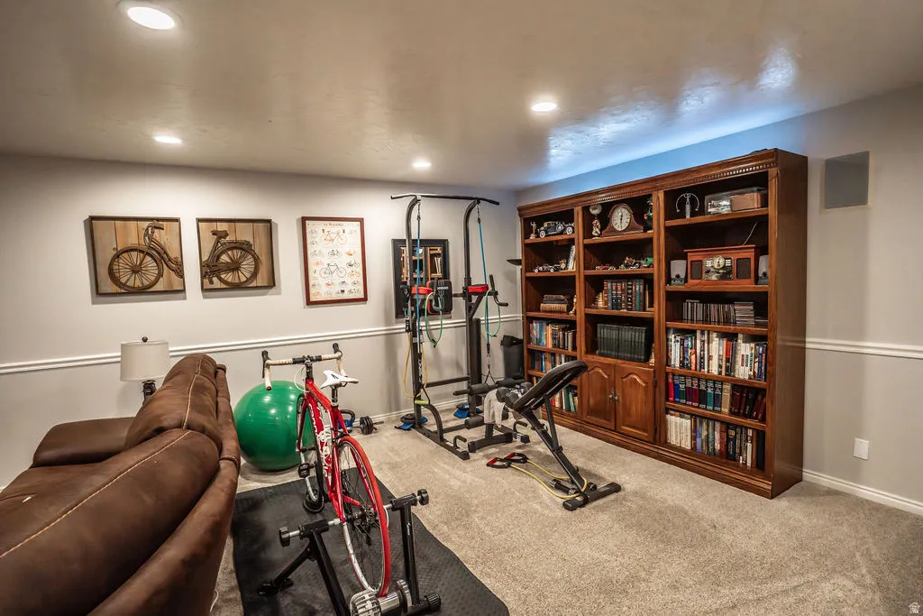 Built-in wood bookcase with extensive shelving and storage, recessed lighting, wall-to-wall carpeting, and chair rail molding