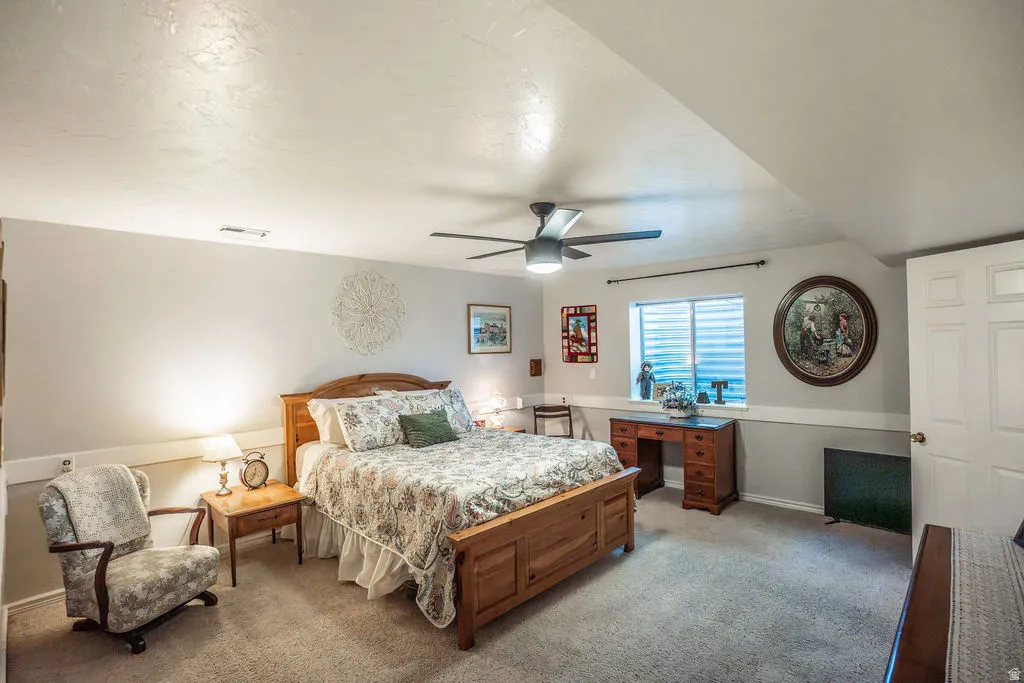 Carpeted bedroom featuring a ceiling fan with integrated lighting, a window with horizontal blinds, and a white paneled door