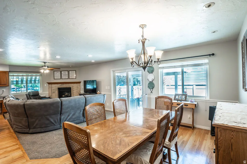 Open-concept living area featuring a central dining space with wood-finish flooring, a contemporary chandelier, and a sliding glass door leading to the exterior