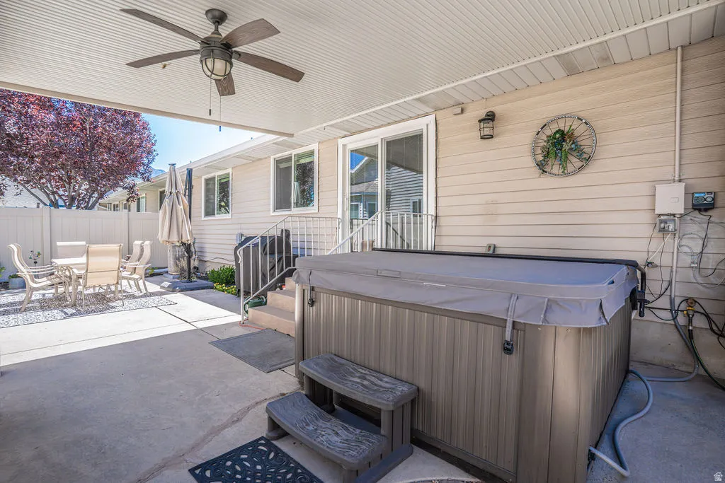 Covered patio featuring a built-in spa with steps, a ceiling fan, and a light fixture
