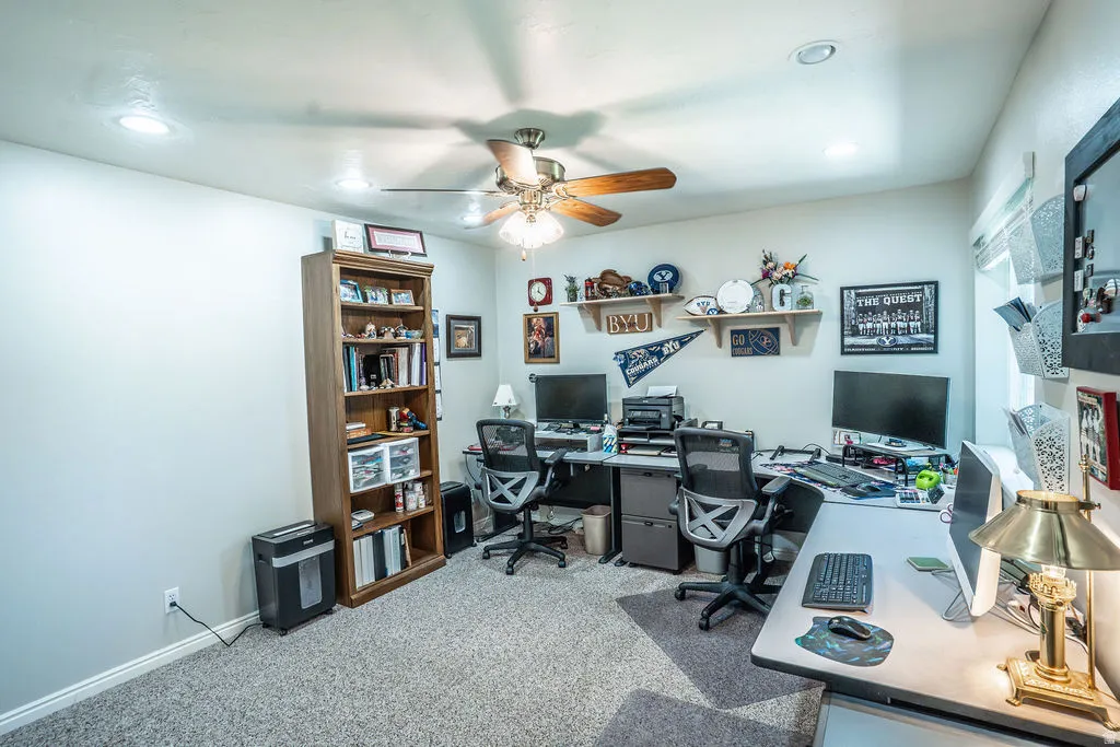 Carpeted room featuring a ceiling fan with integrated lighting, recessed ceiling lights, a window with blinds, and white painted walls