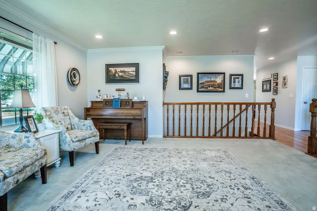 Carpeted living area featuring a large window, recessed lighting, and crown molding