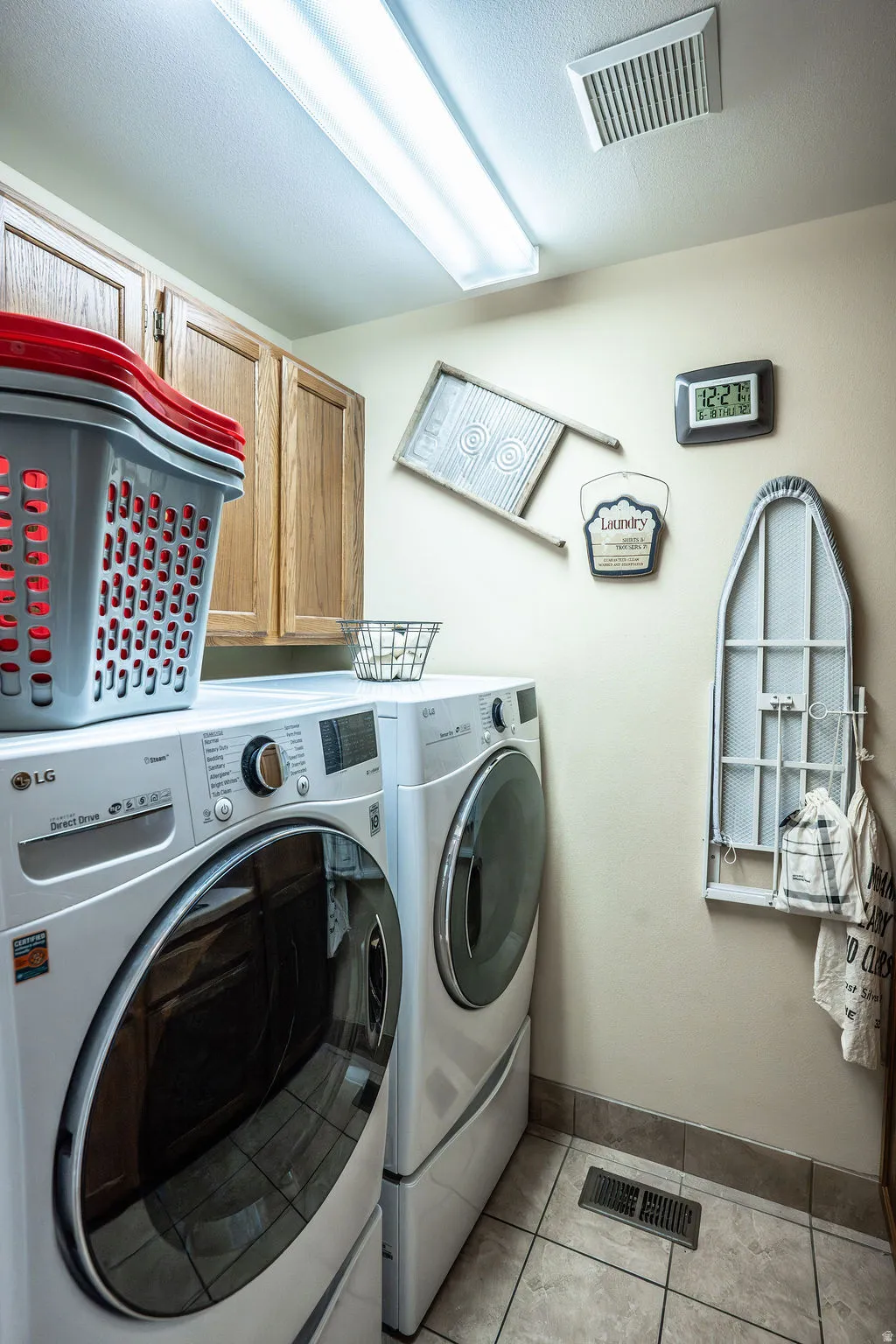 Dedicated laundry area featuring overhead cabinetry, tile flooring, and a fluorescent ceiling light fixture