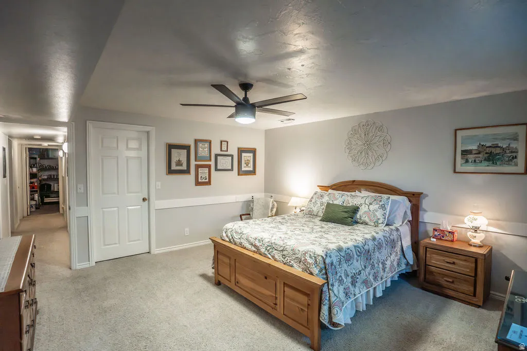 Spacious room featuring light-colored carpeting, a ceiling fan with integrated lighting, and a neutral wall color with a chair rail molding