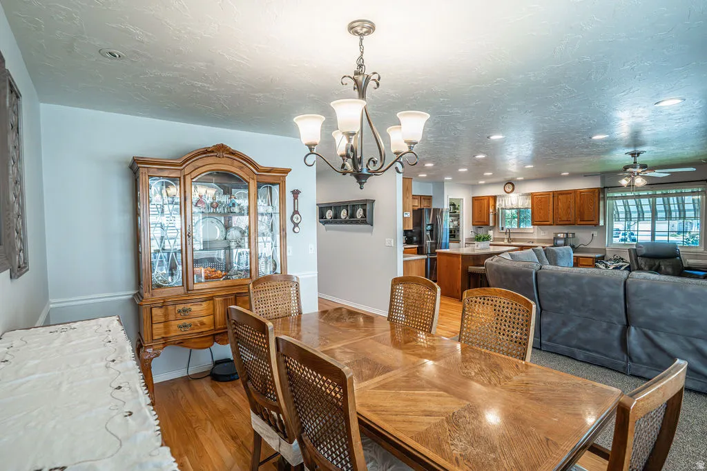 Spacious dining area featuring wood-finish flooring, a decorative chandelier, and an open concept layout connecting to the kitchen and living room