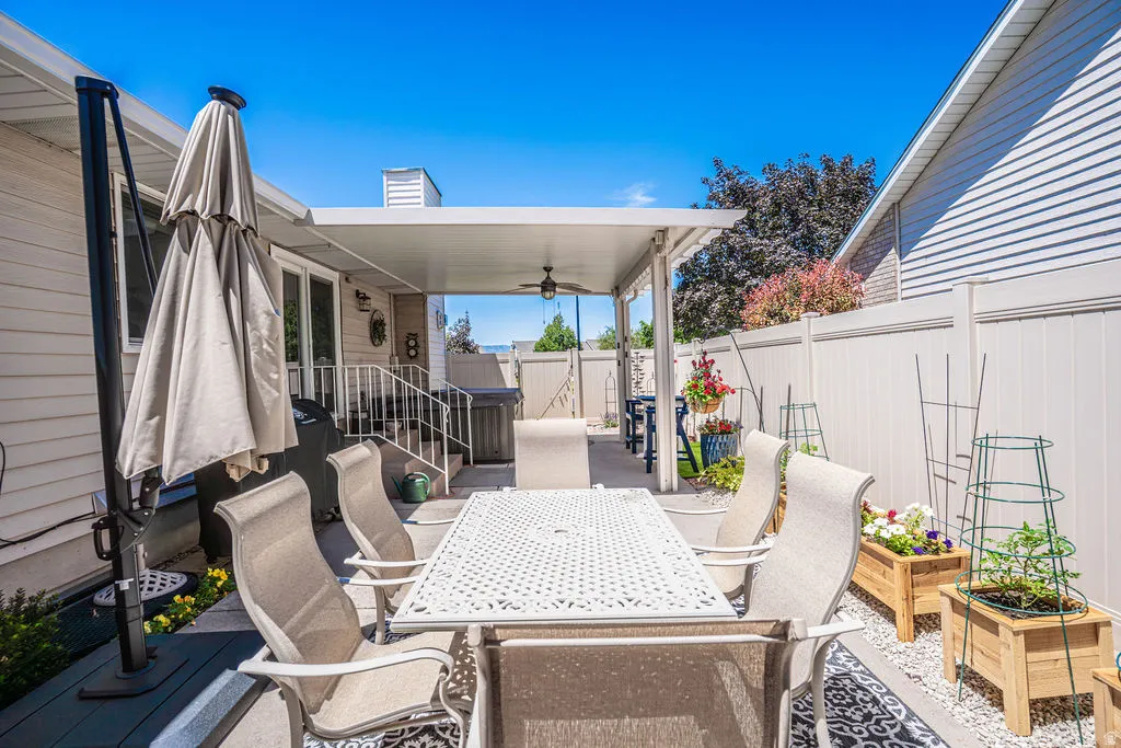 Expansive outdoor patio featuring a solid roof covering, ceiling fan, and privacy fencing