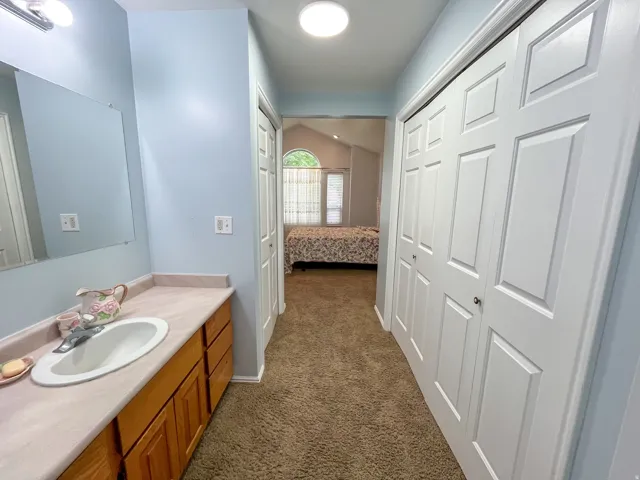 Bathroom vanity featuring a light-toned countertop, an integrated sink, and wood-finish cabinetry