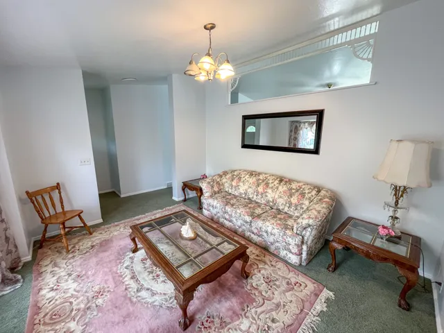 Living area featuring a chandelier light fixture, a decorative interior transom window, and wall-to-wall carpeting