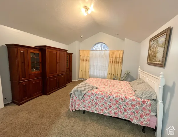 Vaulted ceiling with an arched window, soft gray wall paint, and plush carpeting