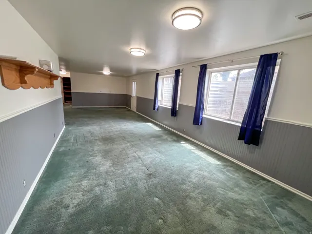 Spacious interior room featuring wall-to-wall carpeting, multiple windows for natural light, and overhead flush-mount lighting fixtures