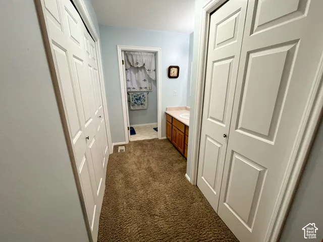 Hallway featuring broadloom carpeting and two sets of white bi-fold closet doors